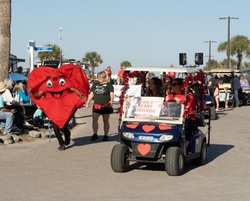 Golf Cart parade with Heart Man Mascot running next to golf cart
