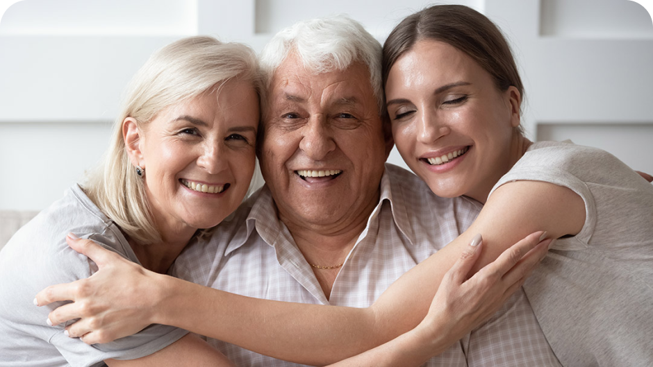 Two parents and adult daughter hugging and smiling