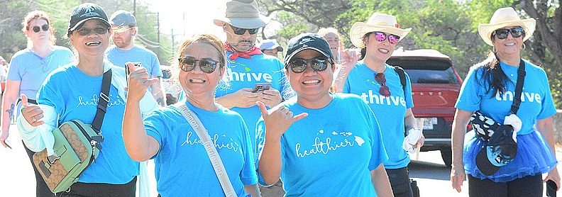 Walkers on the route in blue shirts smiling with some doing shaka hand sign 